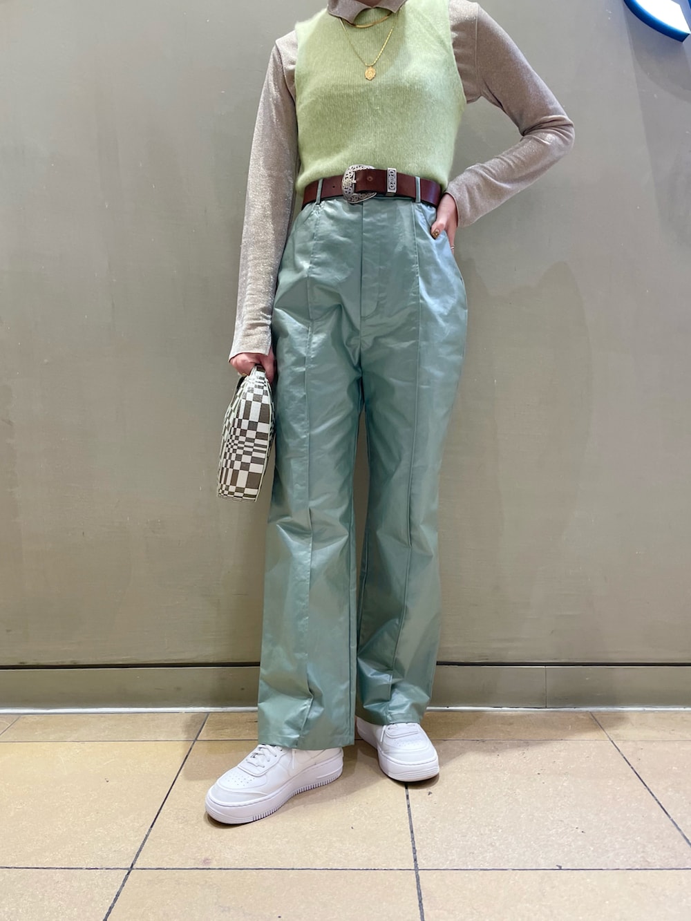 グリーン系のハンドバッグ、ベージュ系のシャツ/ブラウスを着用したレディースの秋コーディネートの2枚目の写真