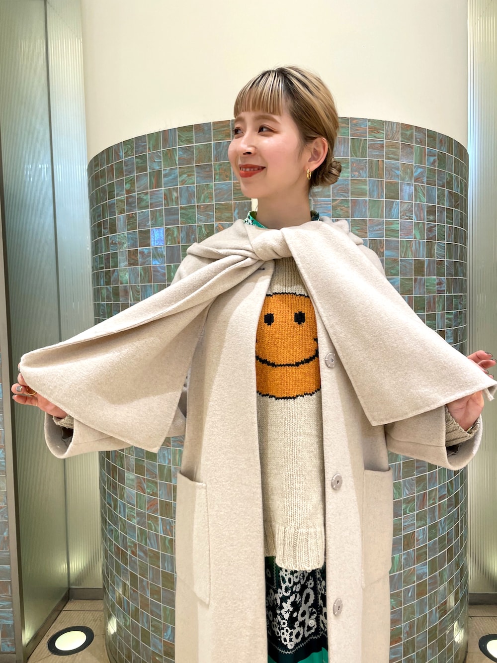 ホワイト系のノーカラーコートを着用したレディースの冬コーディネートの3枚目の写真