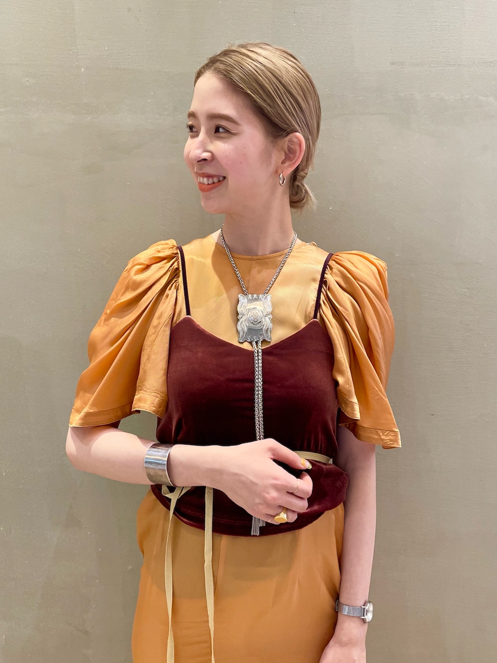 シルバー系のパンプス、ブラウン系のキャミソール、オレンジ系のワンピースを着用したレディースの夏コーディネートの3枚目の写真