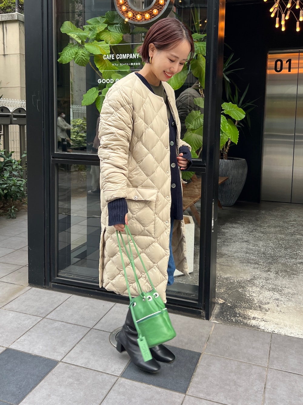 ベージュ系のダウンジャケット/コート、ブルー系のカーディガン/ボレロ、ブラック系のブーツを着用したレディースの冬コーディネートの2枚目の写真