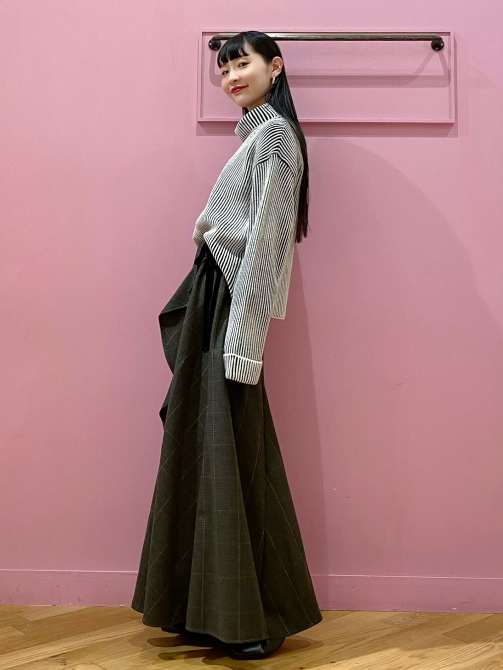 ブラック系のスカート、ブラック系のブーツ、ブラック系のニット/セーターを着用したレディースの秋コーディネートの2枚目の写真