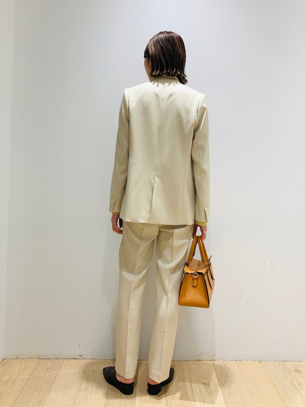 オレンジ系のトートバッグ、ベージュ系のその他アウター、ベージュ系のその他パンツを着用したレディースの冬コーディネートの2枚目の写真