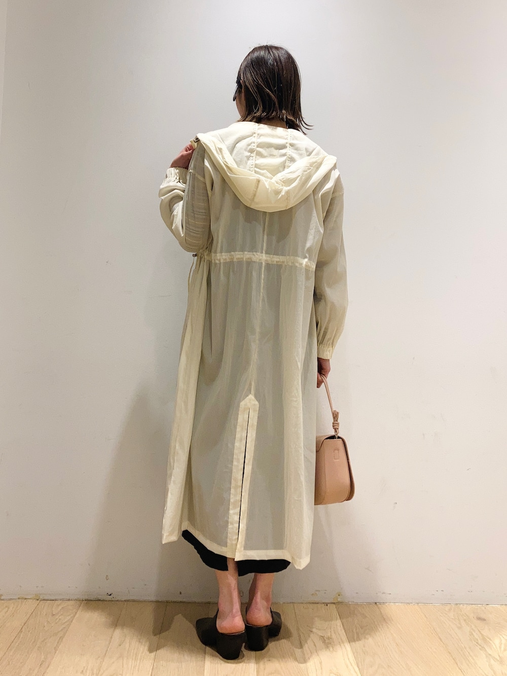 ホワイト系のマウンテンパーカー、ブラック系のジャンパースカート、ピンク系のショルダーバッグを着用したレディースの春コーディネートの2枚目の写真