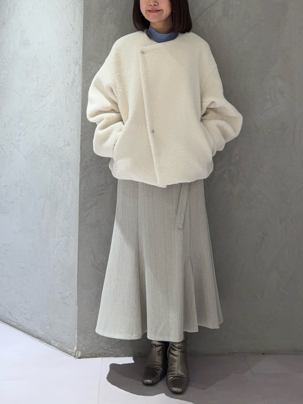 ホワイト系のブルゾン、グレー系のスカート、ブルー系のニット/セーターを着用したレディースの冬コーディネートの5枚目の写真