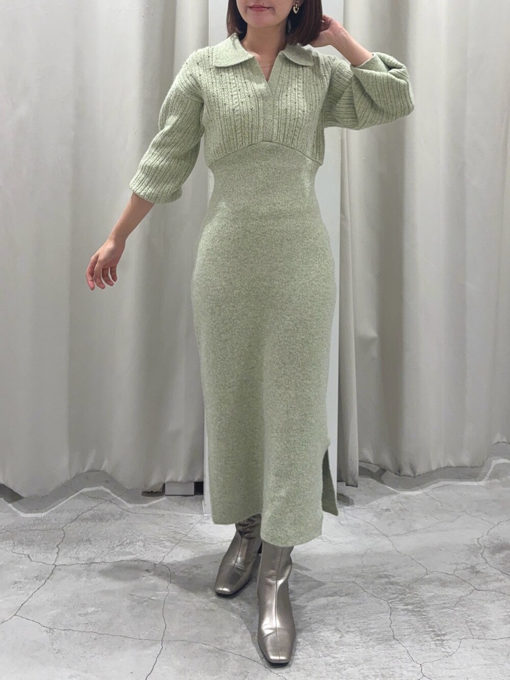 グリーン系のワンピース、シルバー系のブーツ、ゴールド系のイヤリングを着用したレディースの秋コーディネートの4枚目の写真