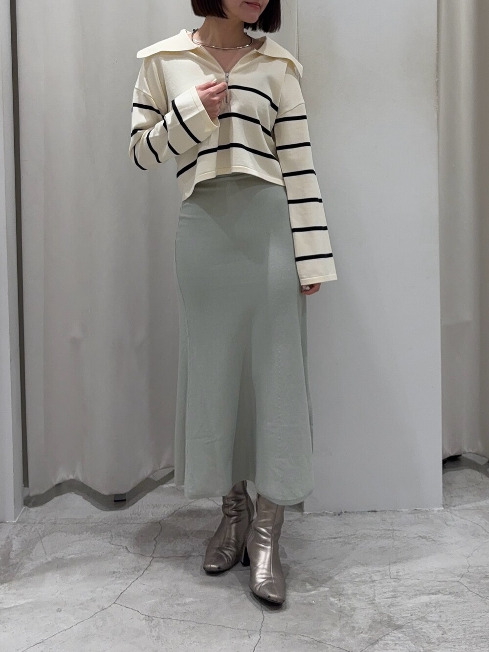 グリーン系のニット/セーター、グリーン系のスカート、シルバー系のブーツを着用したレディースの冬コーディネートの9枚目の写真