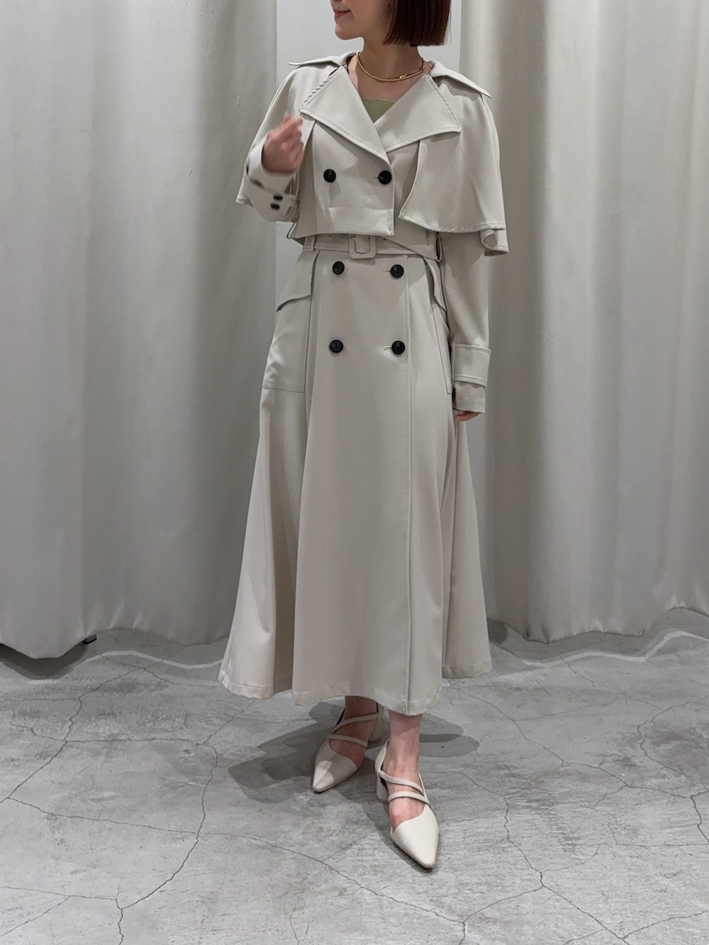 ホワイト系のトレンチコート、グリーン系のニット/セーター、ホワイト系のパンプスを着用したレディースの冬コーディネートの3枚目の写真