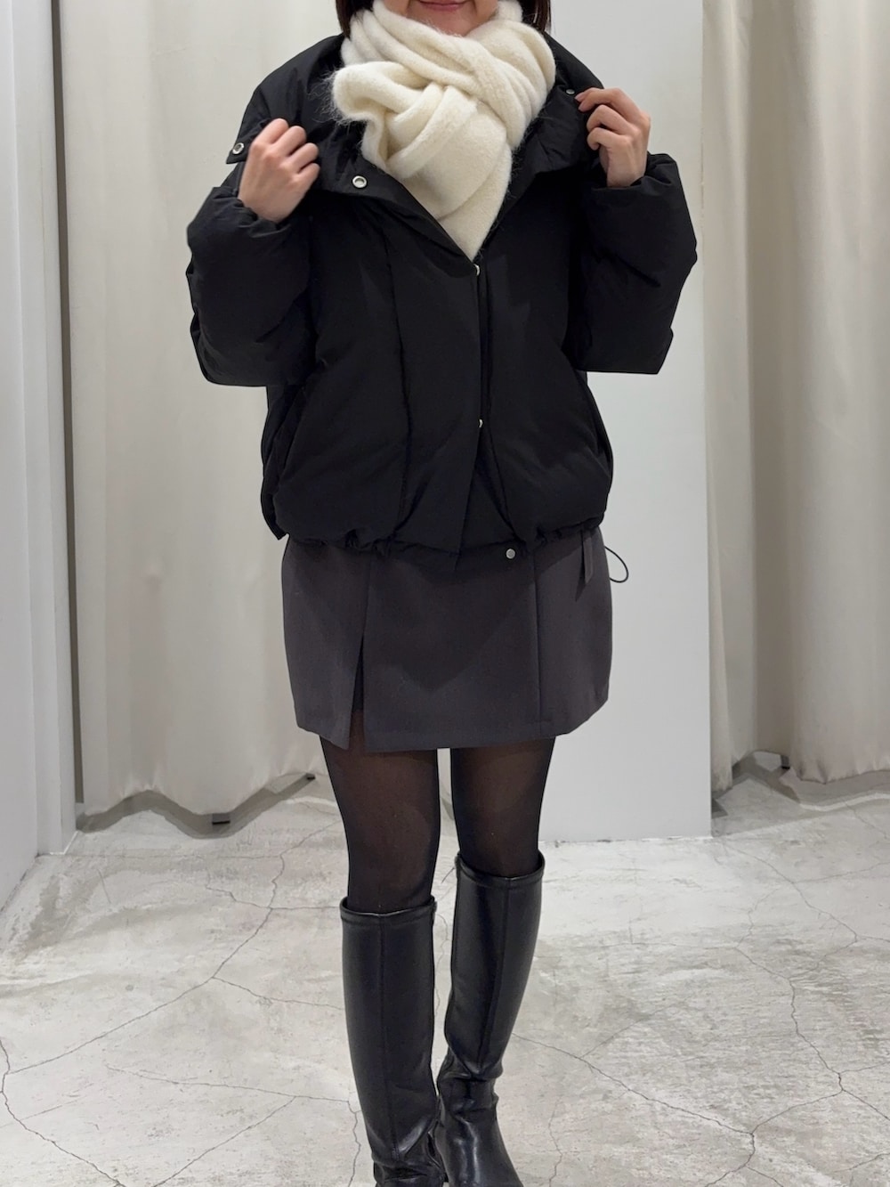 ブラック系のダウンジャケット/コート、グレー系のスカート、ブラック系のニット/セーターを着用したレディースの冬コーディネートの3枚目の写真