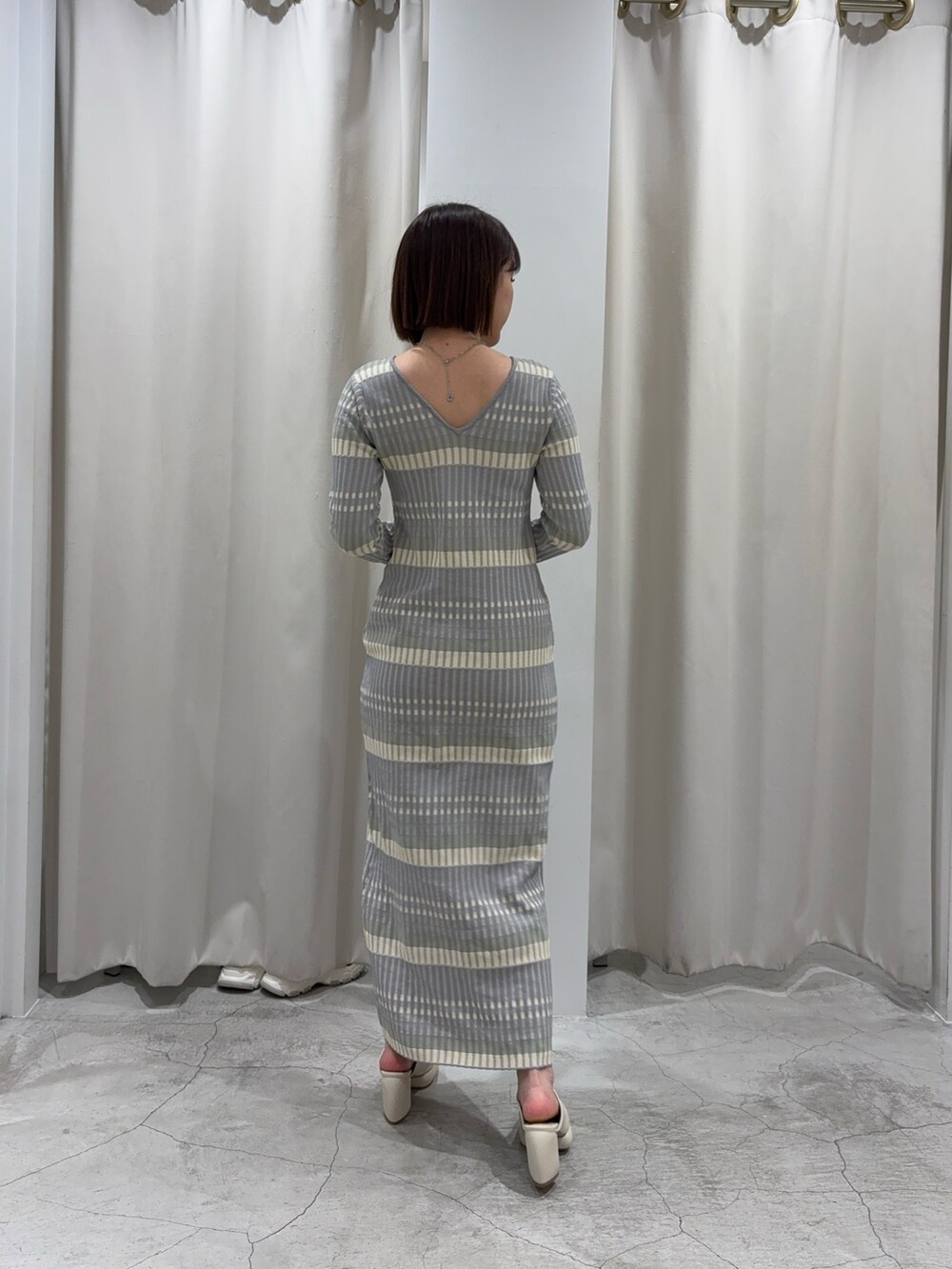 グレー系のワンピース、ホワイト系のカーディガン/ボレロ、ホワイト系のサンダルを着用したレディースの冬コーディネートの5枚目の写真