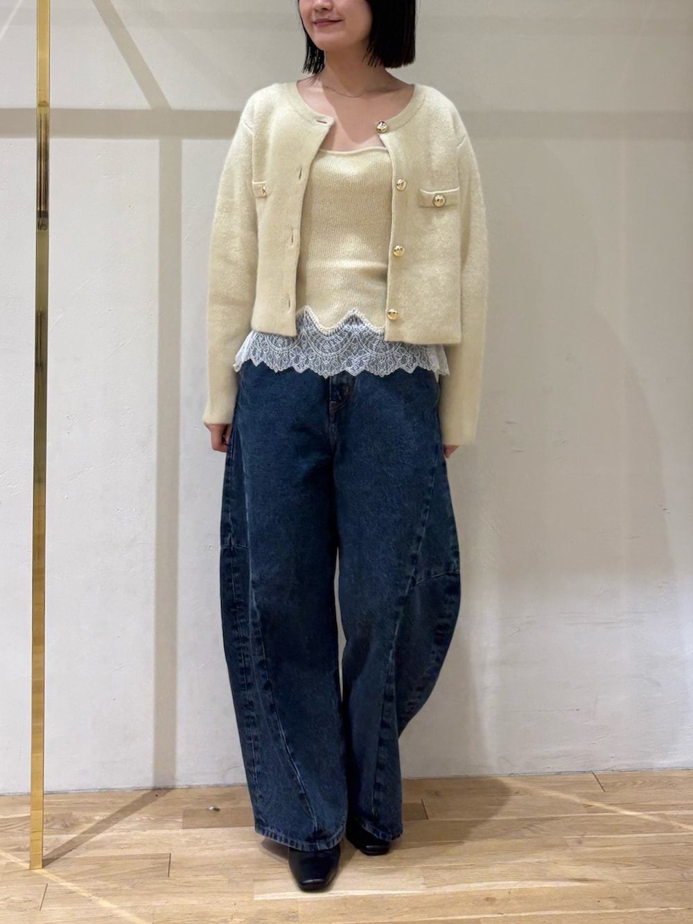イエロー系のノーカラージャケット、イエロー系のキャミソール、ブルー系のデニムパンツを着用したレディースの秋コーディネートの2枚目の写真