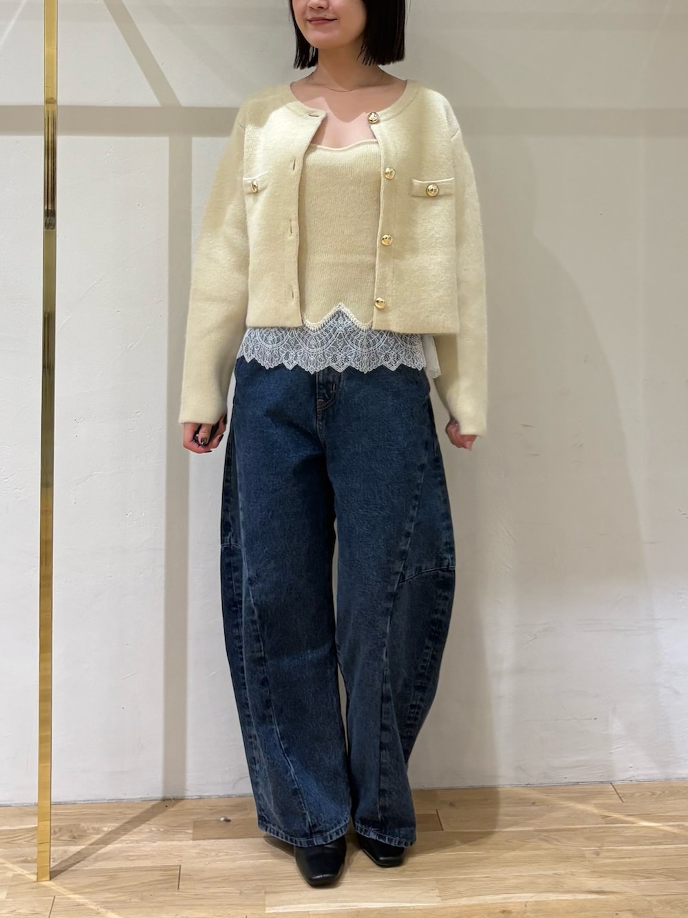 イエロー系のノーカラージャケット、イエロー系のキャミソール、ブルー系のデニムパンツを着用したレディースの秋コーディネートの8枚目の写真