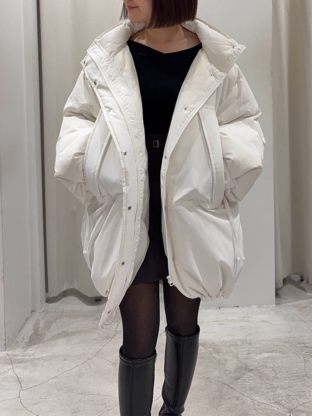 ブラック系のショルダーバッグ、グレー系のスカート、ホワイト系のダウンジャケット/コートを着用したレディースの冬コーディネートの3枚目の写真