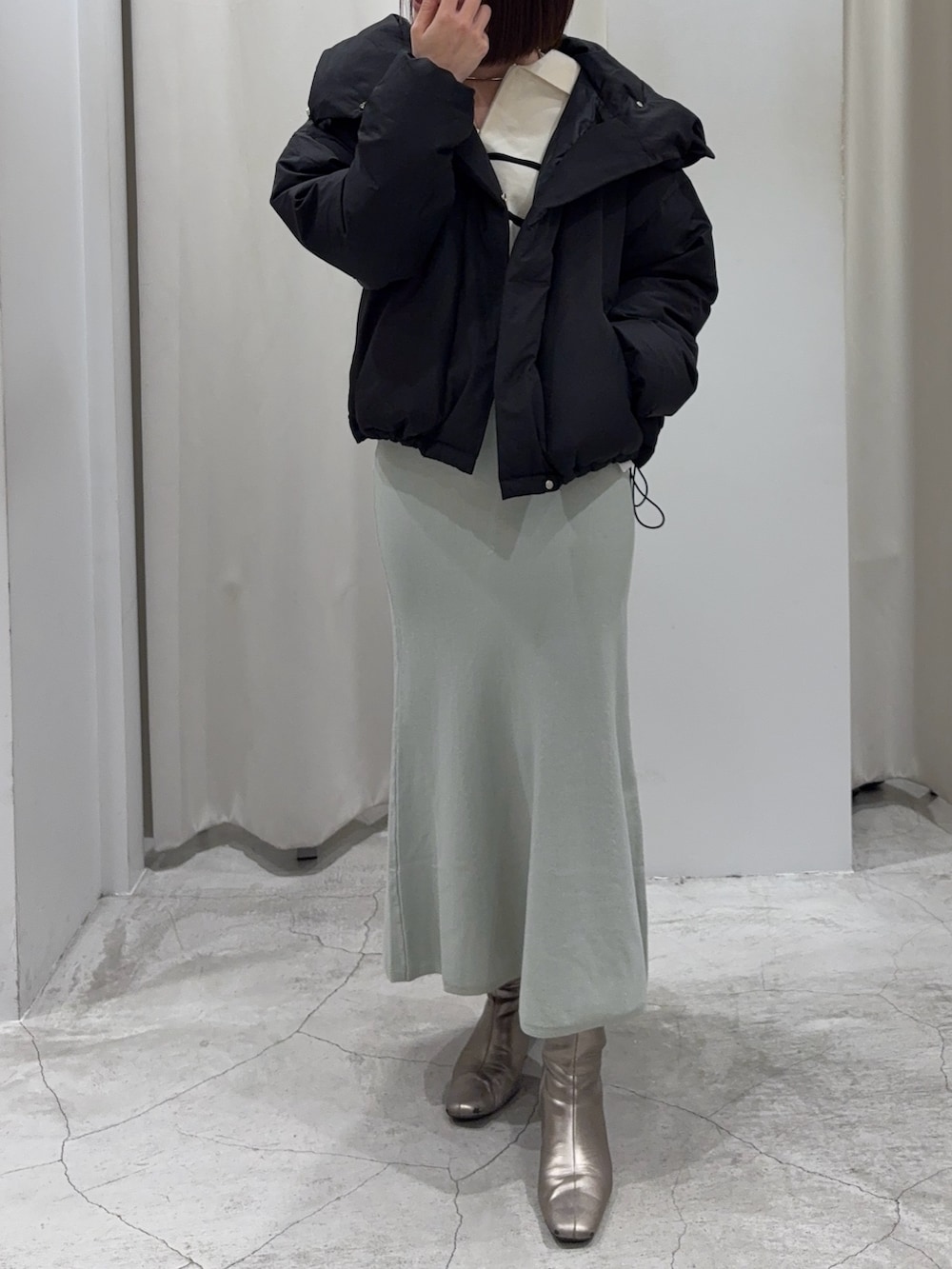 ブラック系のダウンジャケット/コート、ホワイト系のニット/セーター、グリーン系のスカートを着用したレディースの冬コーディネートの5枚目の写真