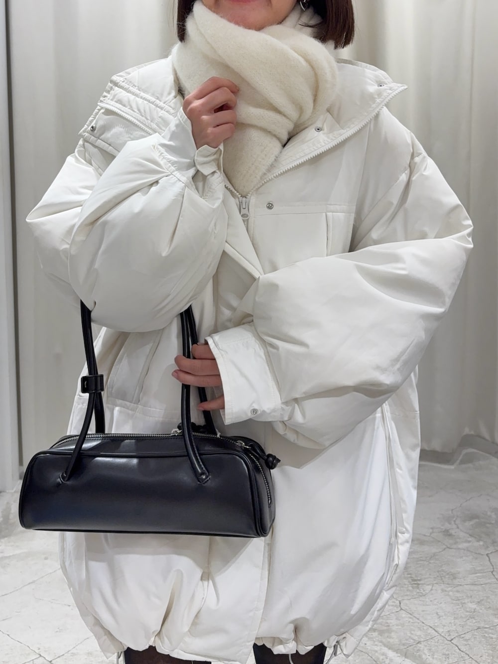 ブラック系のショルダーバッグ、グレー系のスカート、ホワイト系のダウンジャケット/コートを着用したレディースの冬コーディネートの6枚目の写真