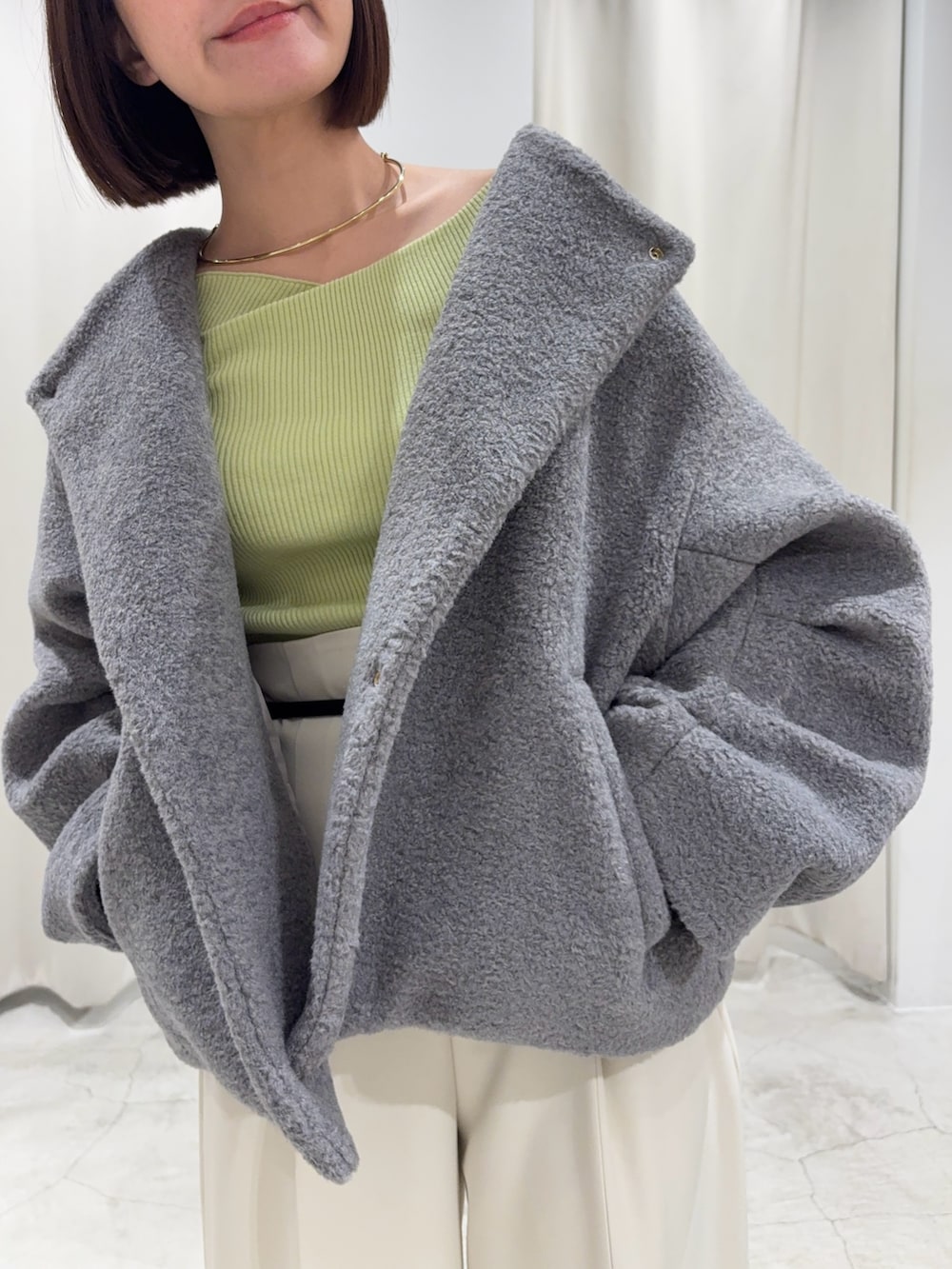 グリーン系のニット/セーター、グレー系のブルゾン、ホワイト系のその他パンツを着用したレディースの冬コーディネートの8枚目の写真