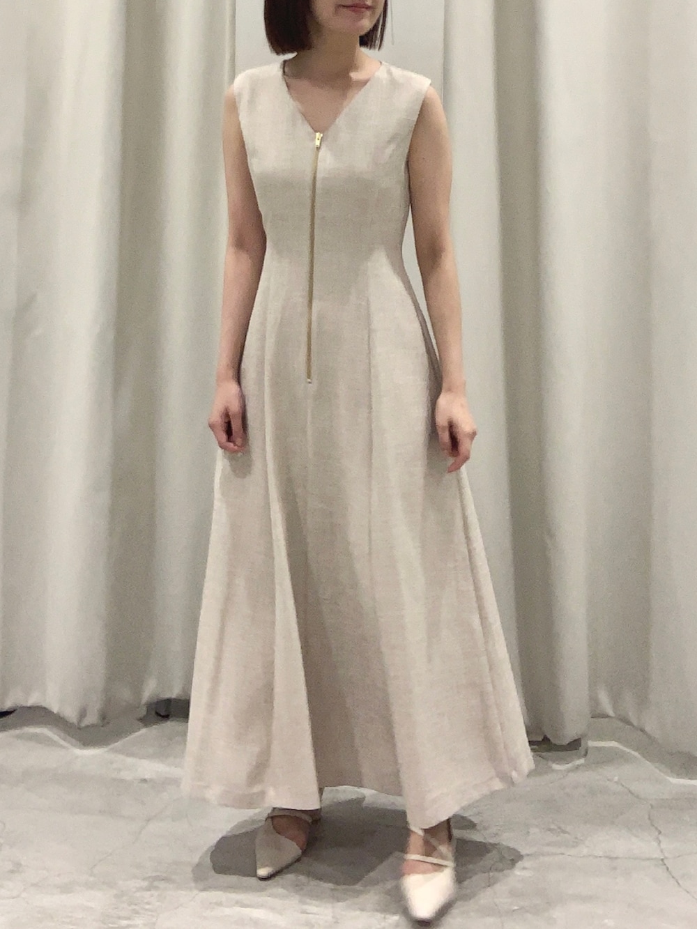 ベージュ系のワンピース、ホワイト系のショルダーバッグ、ホワイト系のパンプスを着用したレディースの夏コーディネートの2枚目の写真