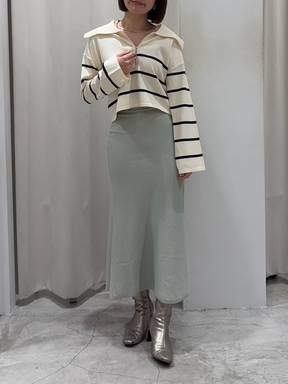 ブラック系のダウンジャケット/コート、ホワイト系のニット/セーター、グリーン系のスカートを着用したレディースの冬コーディネートの4枚目の写真