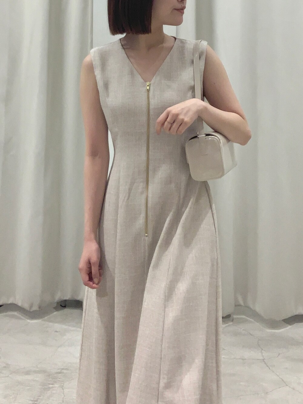 ベージュ系のワンピース、ホワイト系のショルダーバッグ、ホワイト系のパンプスを着用したレディースの夏コーディネートの7枚目の写真