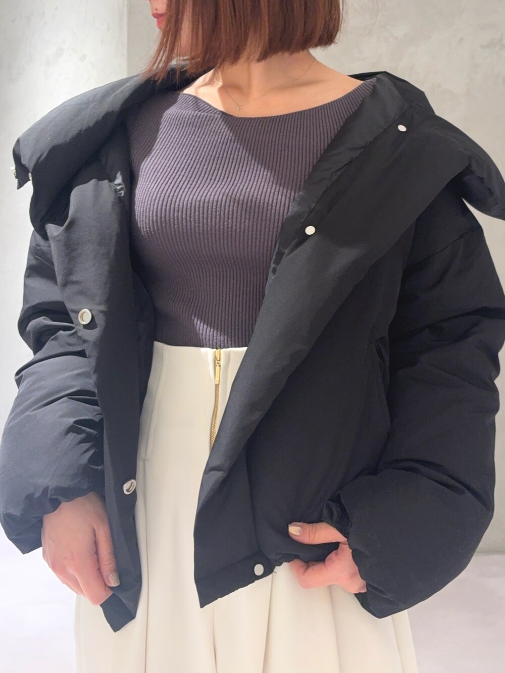 グレー系のニット/セーター、ホワイト系のその他パンツ、ブラック系のダウンジャケット/コートを着用したレディースの秋コーディネートの2枚目の写真