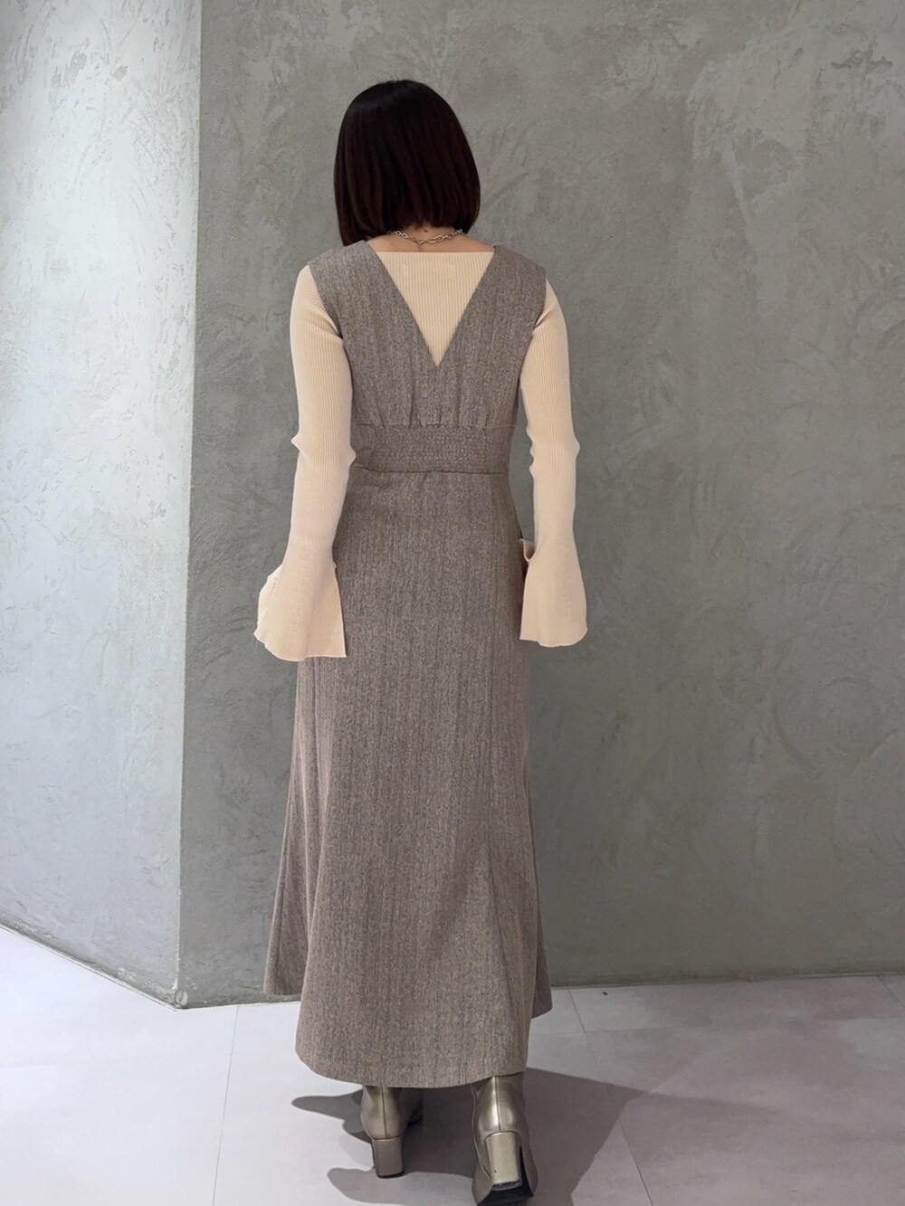 ベージュ系のジャンパースカート、ホワイト系のニット/セーター、シルバー系のブーツを着用したレディースの冬コーディネートの3枚目の写真