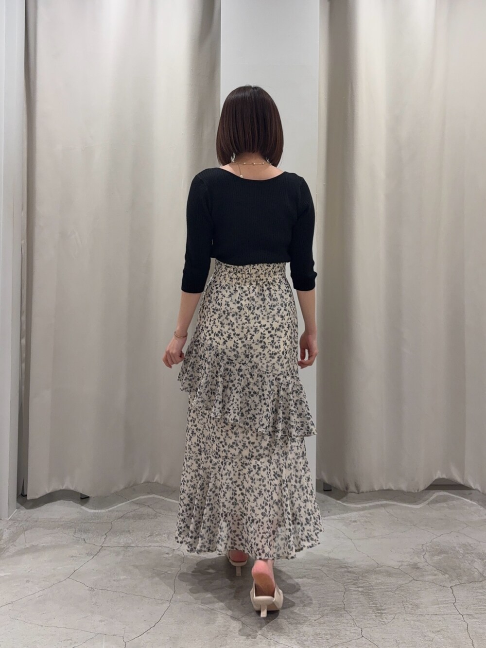 ホワイト系のスカート、ブラック系のニット/セーター、ホワイト系のサンダルを着用したレディースの春コーディネートの4枚目の写真