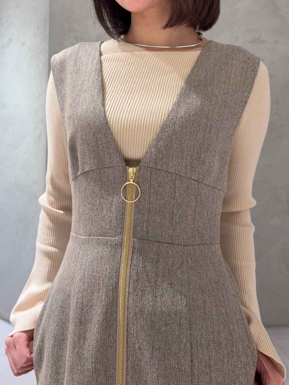 ベージュ系のジャンパースカート、ホワイト系のニット/セーター、シルバー系のブーツを着用したレディースの冬コーディネートの2枚目の写真