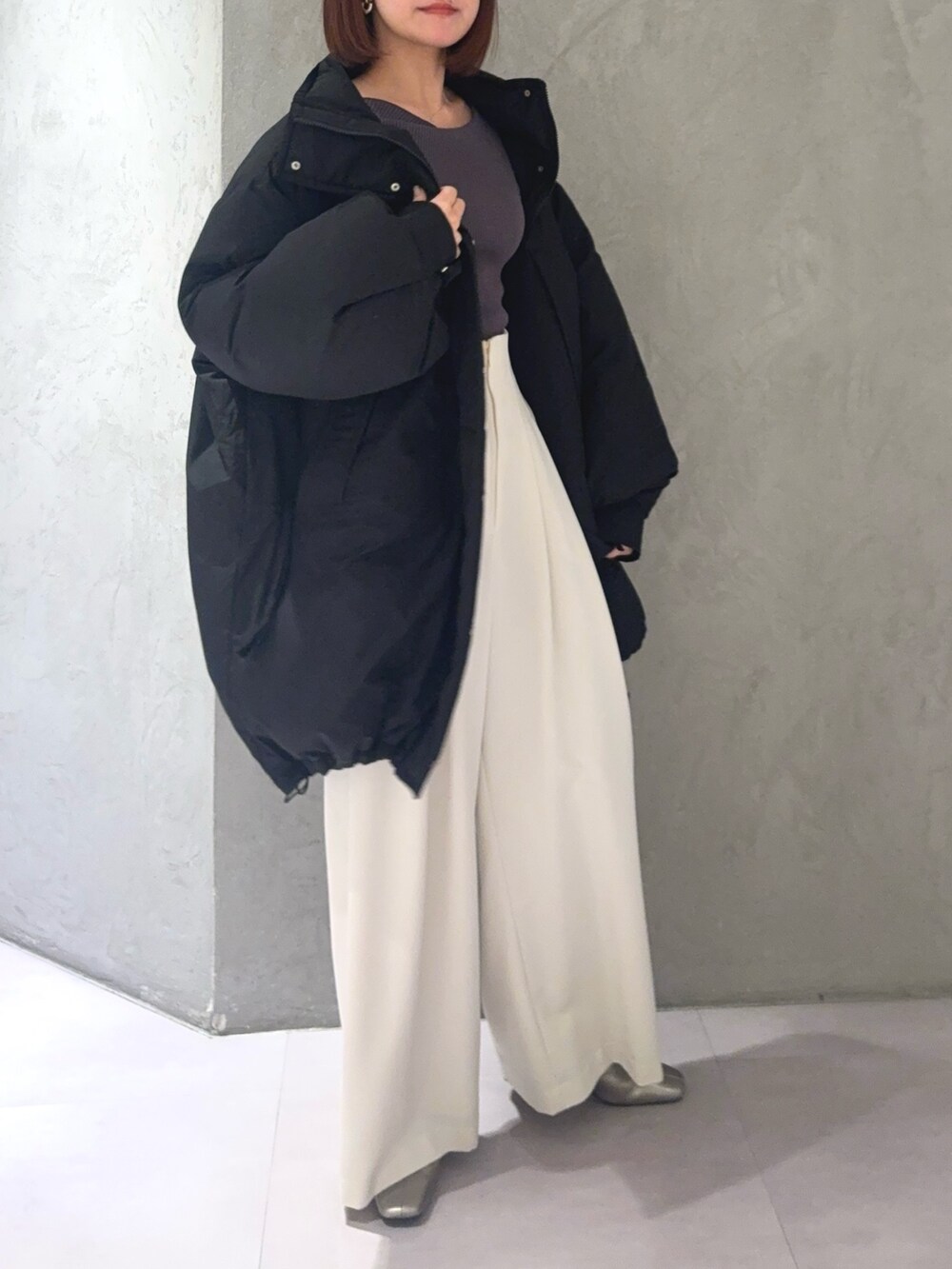 グレー系のニット/セーター、ホワイト系のその他パンツ、ブラック系のダウンジャケット/コートを着用したレディースの秋コーディネートの5枚目の写真