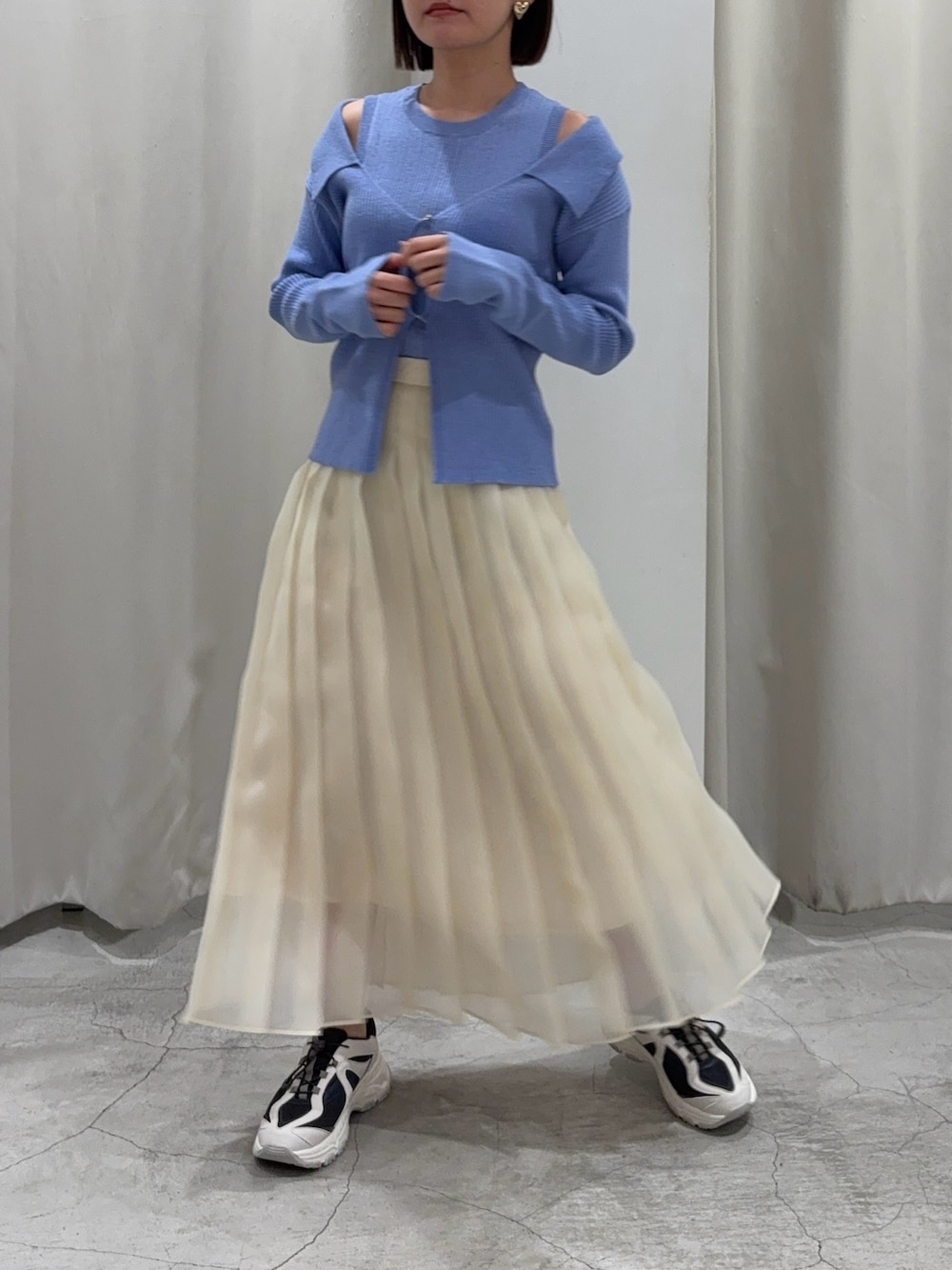 ブルー系のアンサンブル、ホワイト系のスカート、グレー系のスニーカーを着用したレディースの冬コーディネートの2枚目の写真