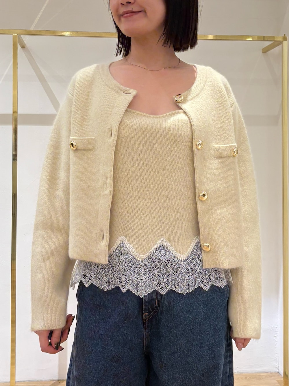 イエロー系のノーカラージャケット、イエロー系のキャミソール、ブルー系のデニムパンツを着用したレディースの秋コーディネートの6枚目の写真