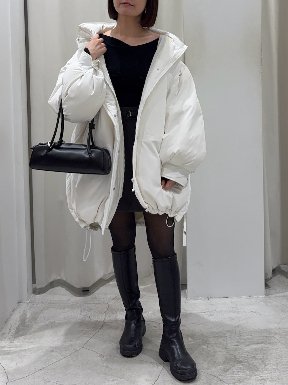 ブラック系のショルダーバッグ、グレー系のスカート、ホワイト系のダウンジャケット/コートを着用したレディースの冬コーディネートの2枚目の写真