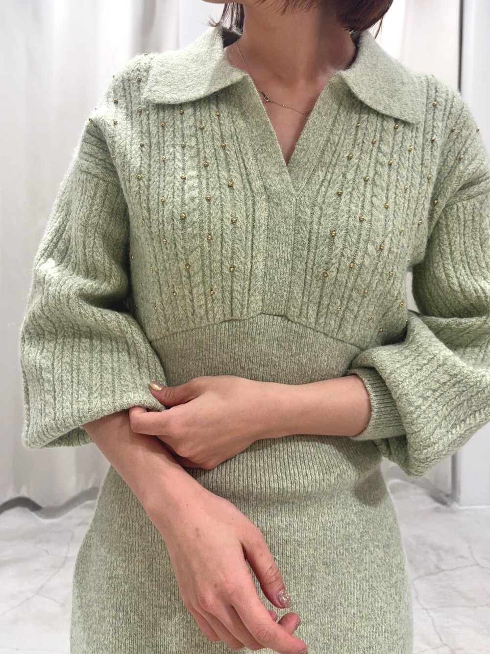 グリーン系のワンピース、シルバー系のブーツ、ゴールド系のイヤリングを着用したレディースの秋コーディネートの5枚目の写真