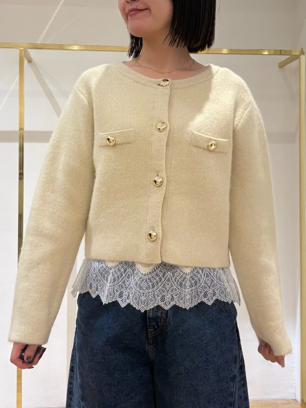 イエロー系のノーカラージャケット、イエロー系のキャミソール、ブルー系のデニムパンツを着用したレディースの秋コーディネートの7枚目の写真