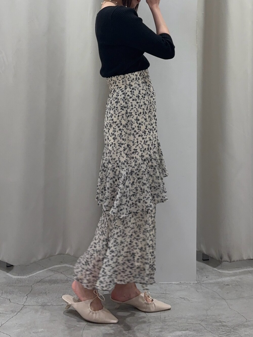 ホワイト系のスカート、ブラック系のニット/セーター、ホワイト系のサンダルを着用したレディースの春コーディネートの5枚目の写真