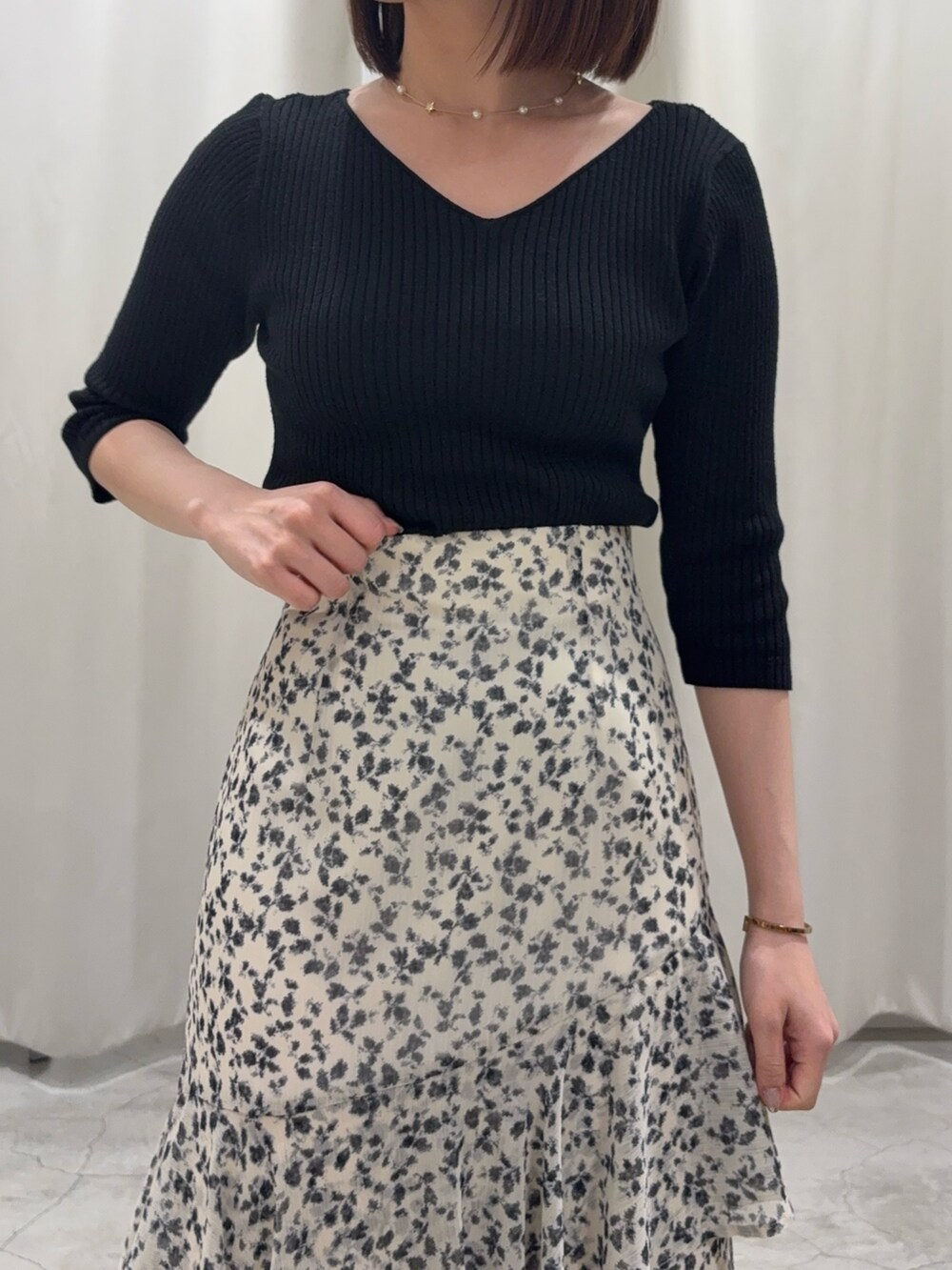 ホワイト系のスカート、ブラック系のニット/セーター、ホワイト系のサンダルを着用したレディースの春コーディネートの3枚目の写真