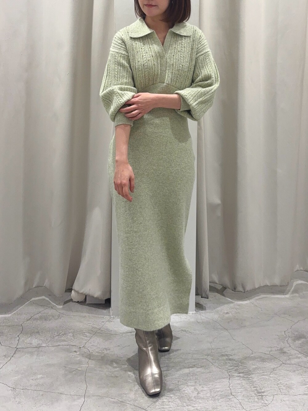 グリーン系のワンピース、シルバー系のブーツ、ゴールド系のイヤリングを着用したレディースの秋コーディネートの7枚目の写真