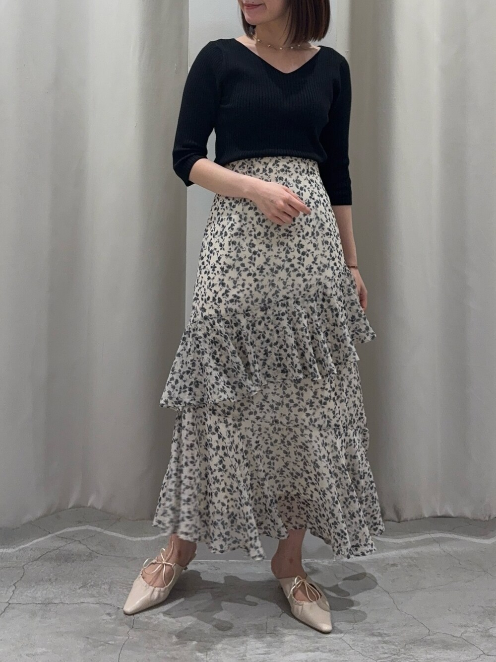 ホワイト系のスカート、ブラック系のニット/セーター、ホワイト系のサンダルを着用したレディースの春コーディネートの6枚目の写真