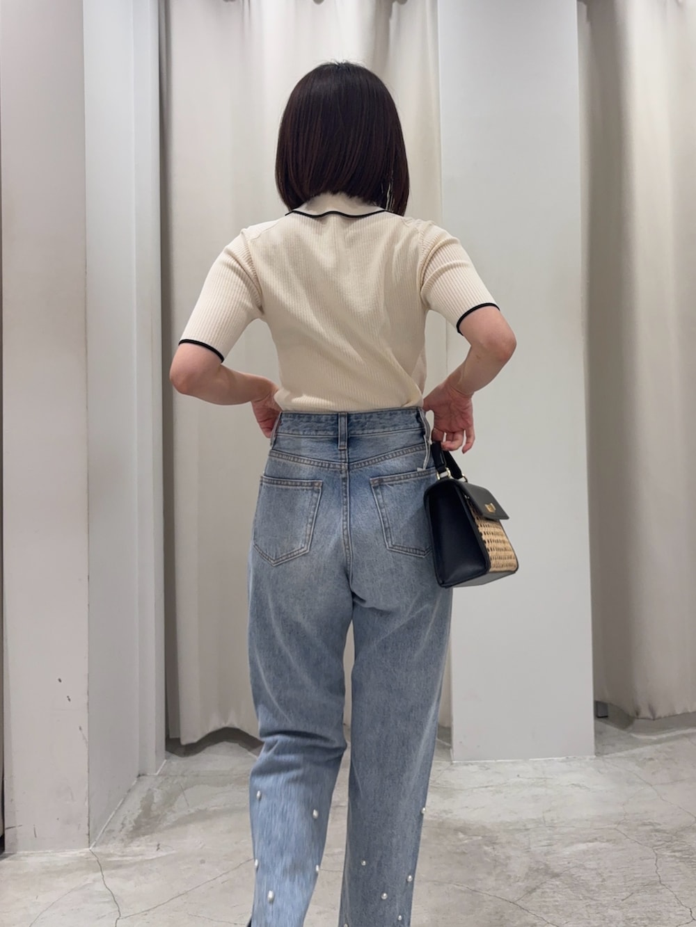 ブルー系のデニムパンツ、ブラック系のハンドバッグ、ホワイト系のニット/セーターを着用したレディースの春コーディネートの4枚目の写真