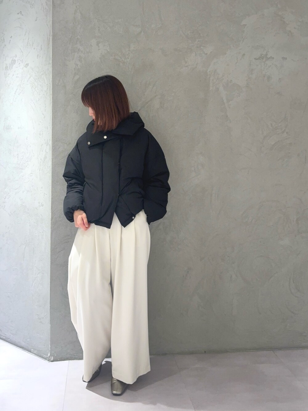 グレー系のニット/セーター、ホワイト系のその他パンツ、ブラック系のダウンジャケット/コートを着用したレディースの秋コーディネートの3枚目の写真