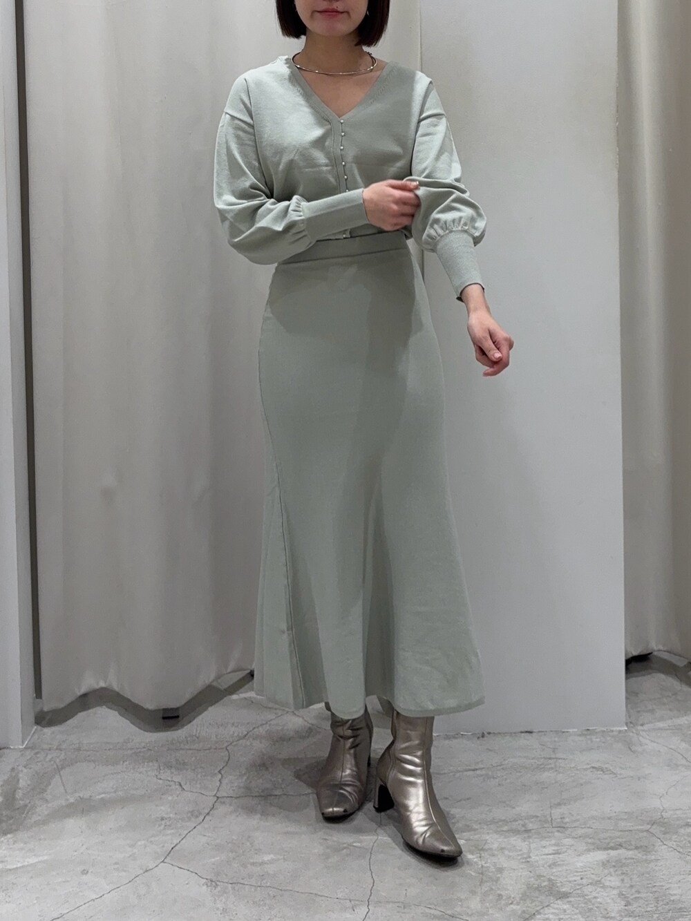 グリーン系のニット/セーター、グリーン系のスカート、シルバー系のブーツを着用したレディースの冬コーディネートの10枚目の写真