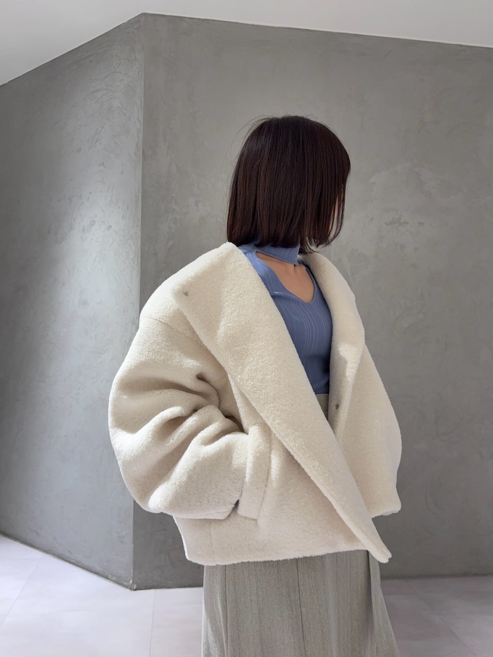 ホワイト系のブルゾン、グレー系のスカート、ブルー系のニット/セーターを着用したレディースの冬コーディネートの3枚目の写真