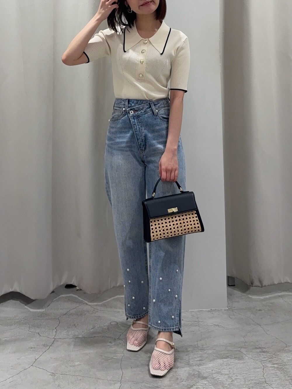 ブルー系のデニムパンツ、ブラック系のハンドバッグ、ホワイト系のニット/セーターを着用したレディースの春コーディネートの2枚目の写真