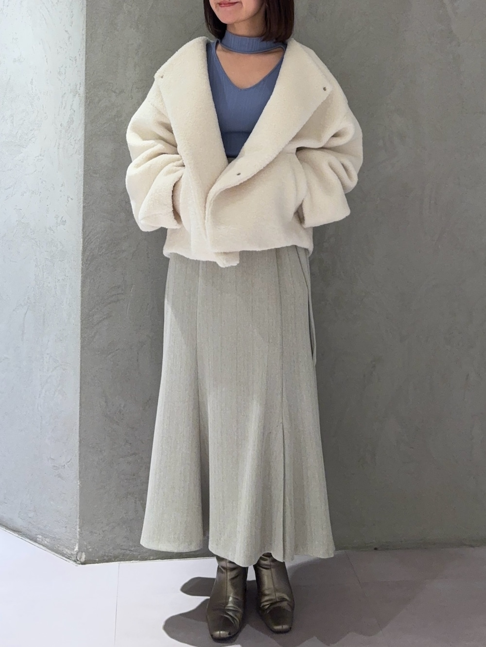ホワイト系のブルゾン、グレー系のスカート、ブルー系のニット/セーターを着用したレディースの冬コーディネートの2枚目の写真