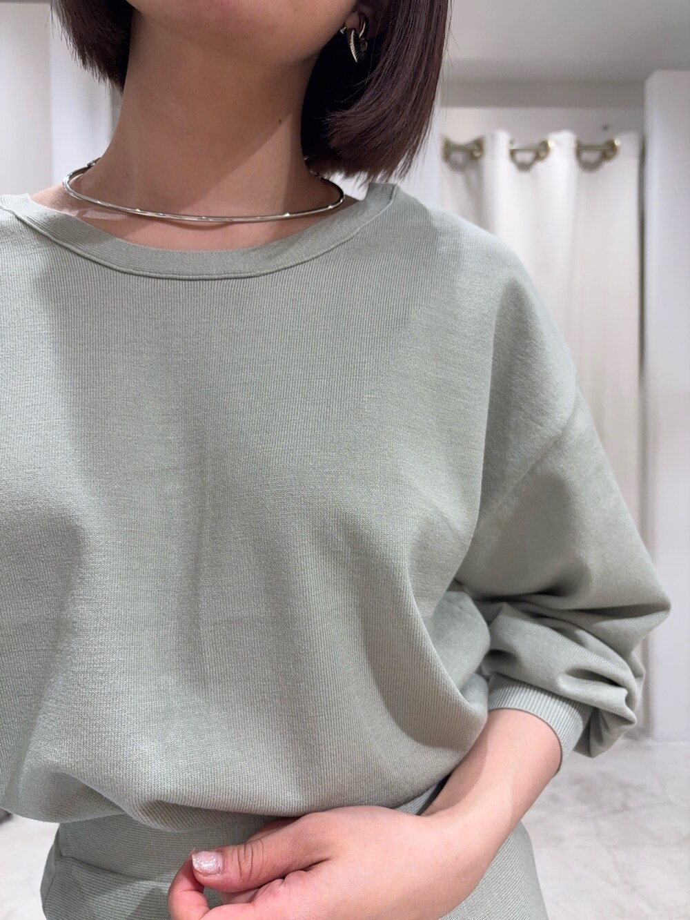 グリーン系のニット/セーター、グリーン系のスカート、シルバー系のブーツを着用したレディースの冬コーディネートの5枚目の写真