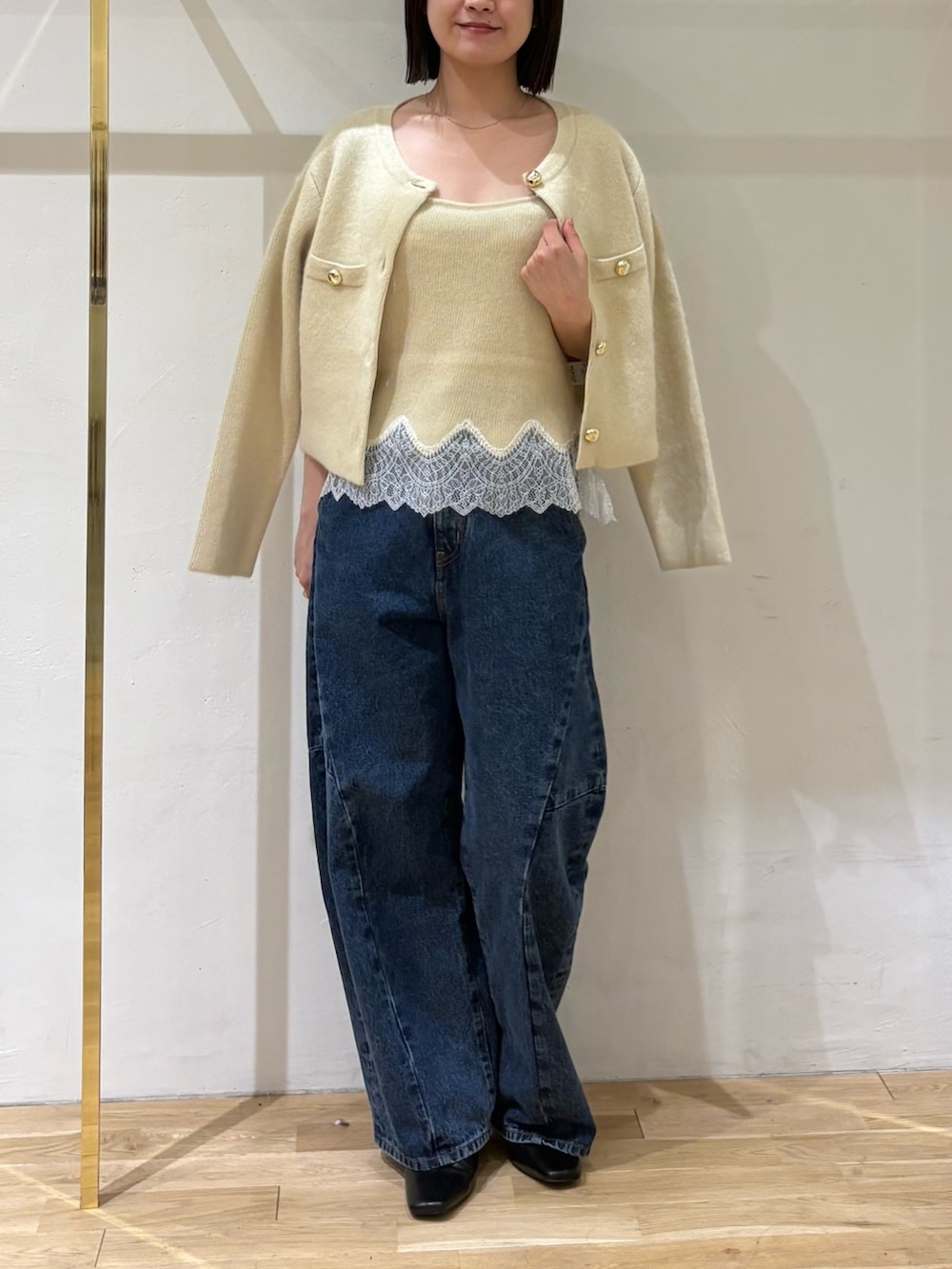 イエロー系のノーカラージャケット、イエロー系のキャミソール、ブルー系のデニムパンツを着用したレディースの秋コーディネートの5枚目の写真