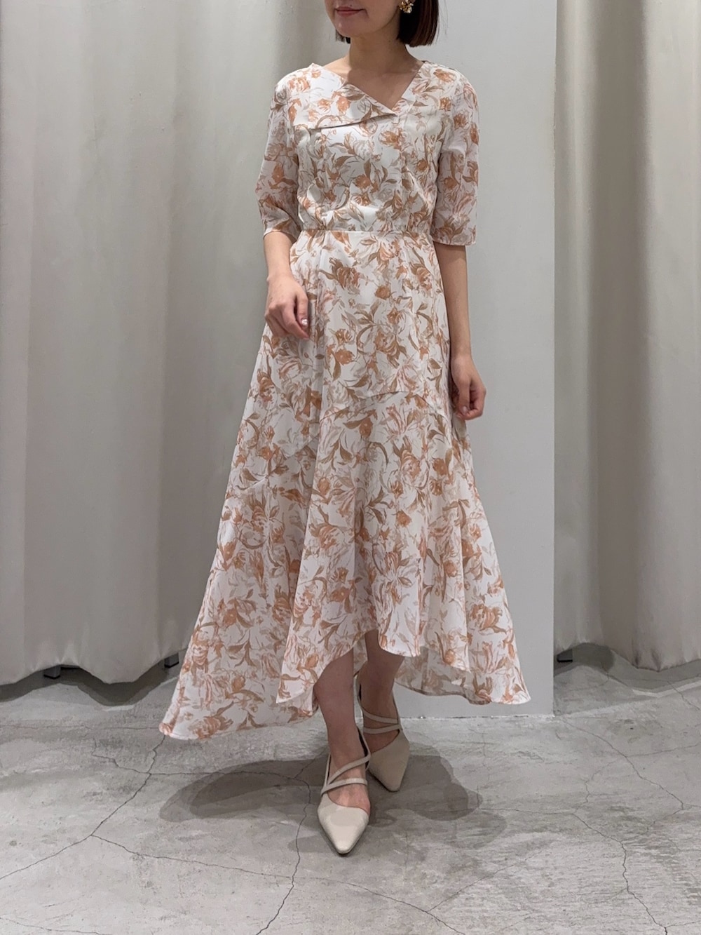 オレンジ系のワンピース、ホワイト系のパンプス、ホワイト系のカーディガン/ボレロを着用したレディースの冬コーディネートの5枚目の写真