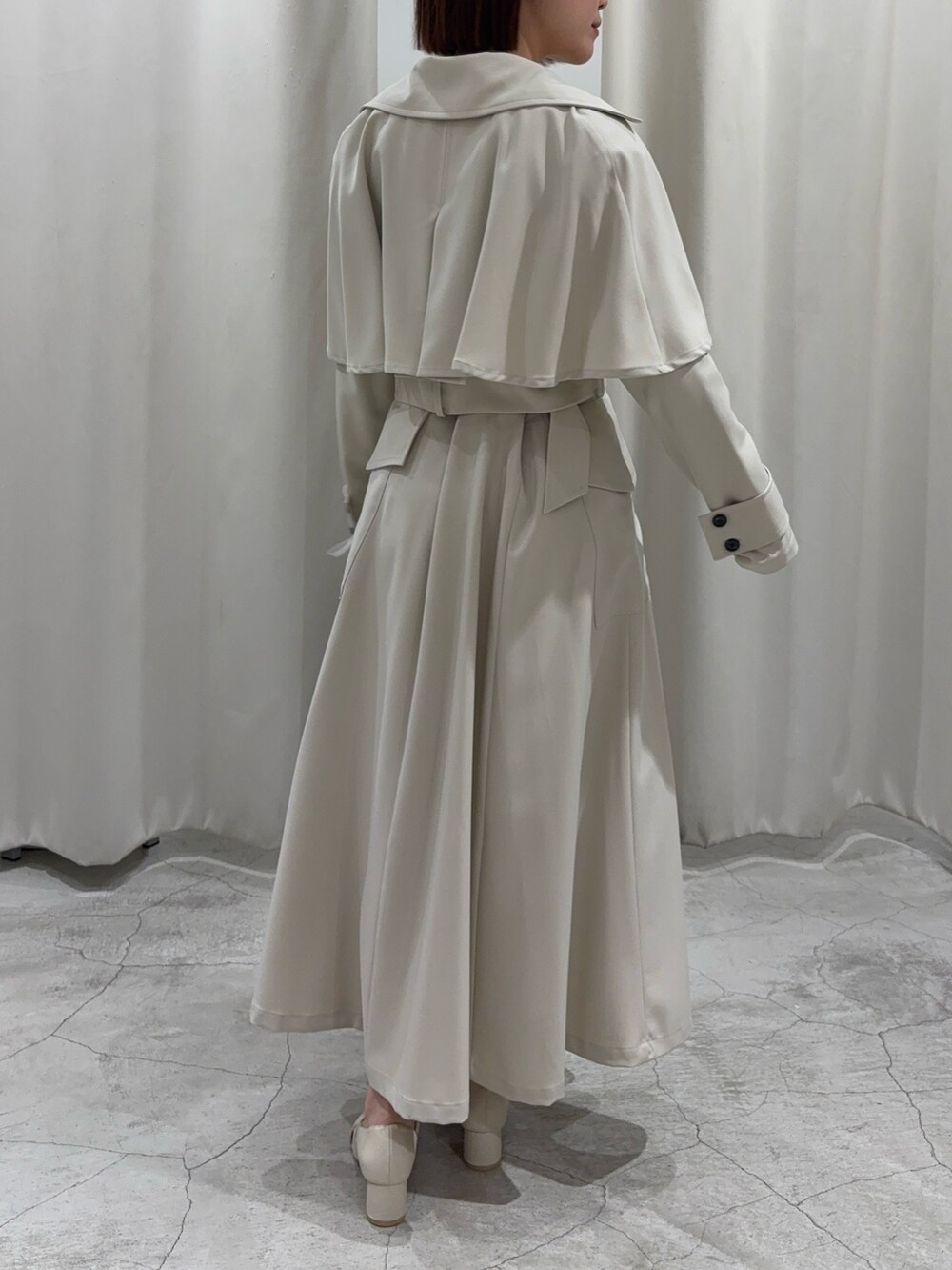 ホワイト系のトレンチコート、グリーン系のニット/セーター、ホワイト系のパンプスを着用したレディースの冬コーディネートの4枚目の写真