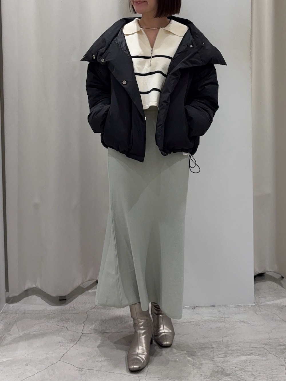 ブラック系のダウンジャケット/コート、ホワイト系のニット/セーター、グリーン系のスカートを着用したレディースの冬コーディネートの6枚目の写真