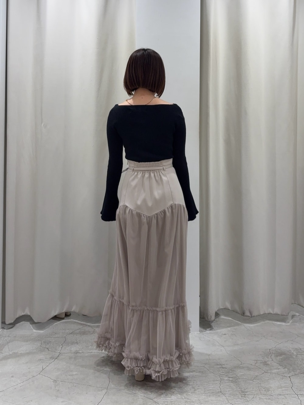 ベージュ系のスカート、ブラック系のニット/セーターを着用したレディースの春コーディネートの3枚目の写真