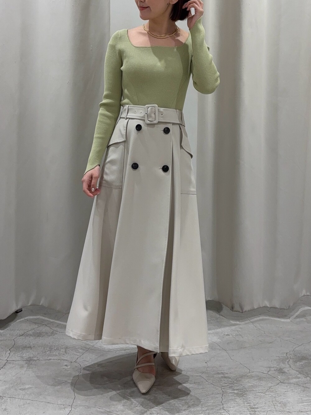 ホワイト系のトレンチコート、グリーン系のニット/セーター、ホワイト系のパンプスを着用したレディースの冬コーディネートの6枚目の写真