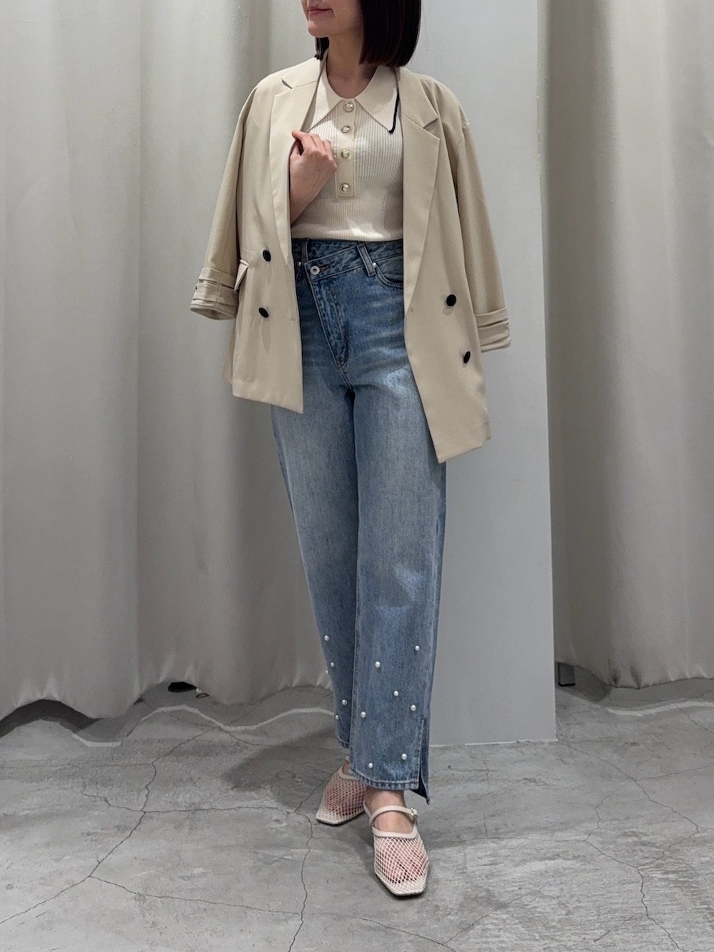 ブルー系のデニムパンツ、ブラック系のハンドバッグ、ホワイト系のニット/セーターを着用したレディースの春コーディネートの5枚目の写真